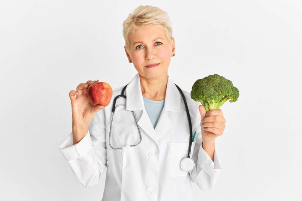 médica recomentando comidas saudáveis como maçã e brócolis