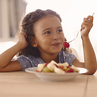 menina comendo salada de frutas