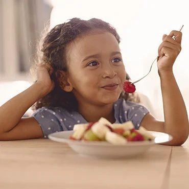 menina comendo salada de frutas